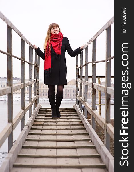 Young girl in the red scarf and black coat standing on stairs. Young girl in the red scarf and black coat standing on stairs