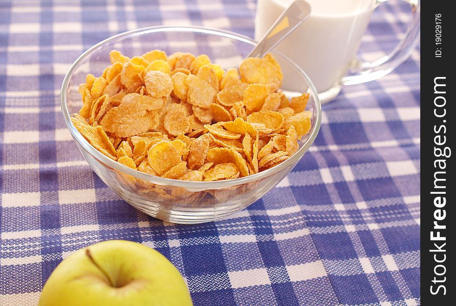 Cornflakes and milk on the table out of the blue tablecloth. Light breakfast.