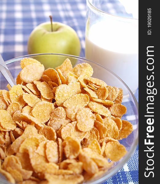 Cornflakes and milk on the table out of the blue tablecloth. Light breakfast.