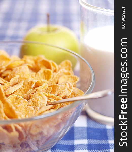 Cornflakes and milk on the table out of the blue tablecloth. Light breakfast.