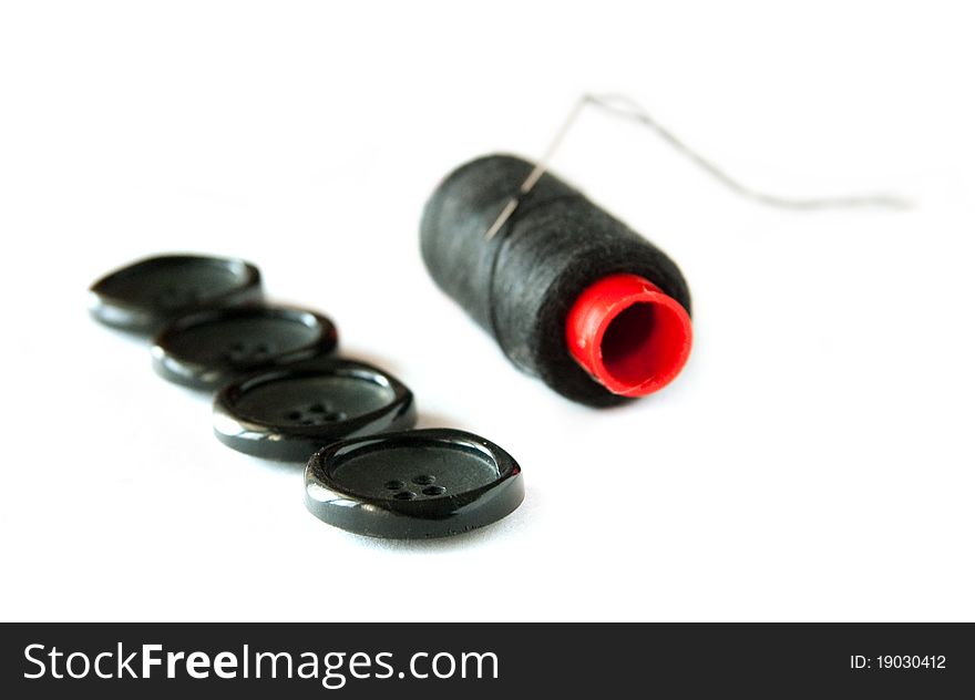 Black buttons with sewing spool and needle islolated on white