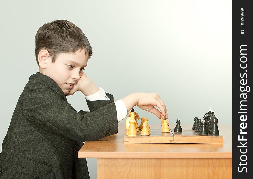 The boy plays chess in a suit. The boy plays chess in a suit