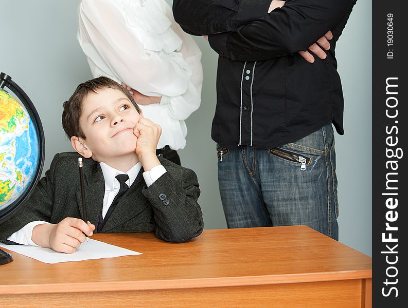 The schoolboy sits at a school desk and dreams