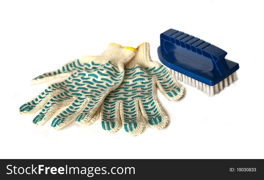 A pair of working gloves and a brush isolated on white. A pair of working gloves and a brush isolated on white