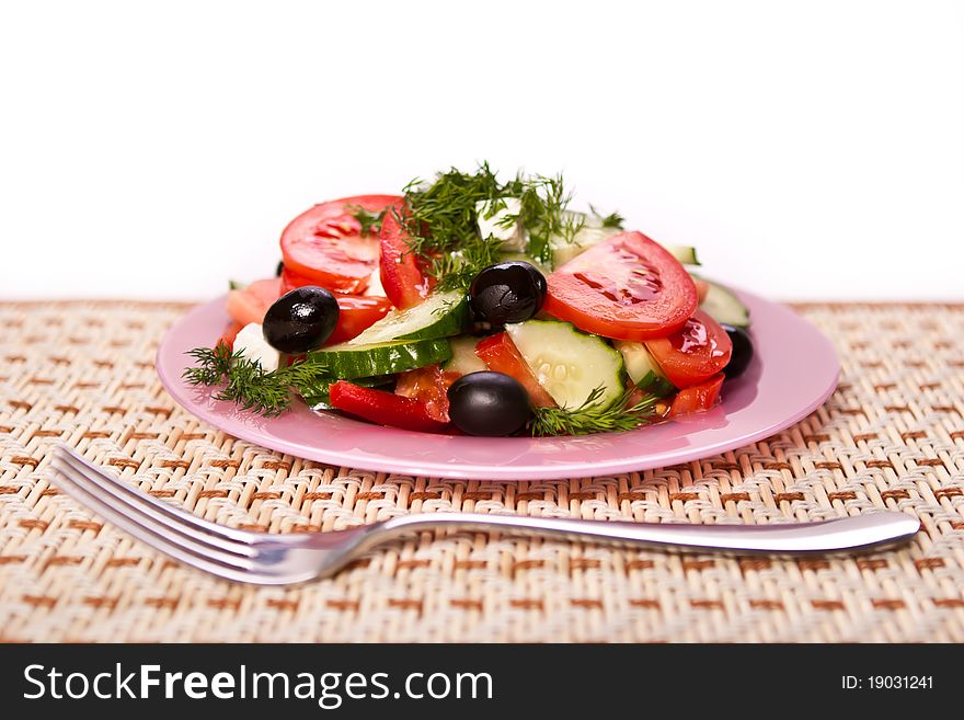 Plate of fresh salad and a fork on the table mat. Plate of fresh salad and a fork on the table mat