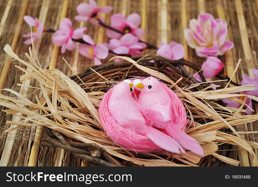 Wicker basket with birds and pink flowers over rustic background. Wicker basket with birds and pink flowers over rustic background