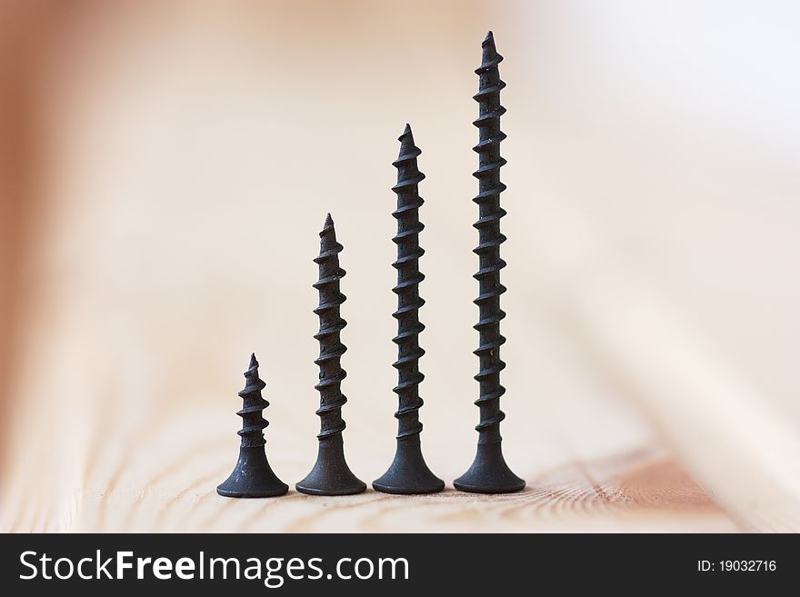 Closeup view of four self-tapped screws over wood background