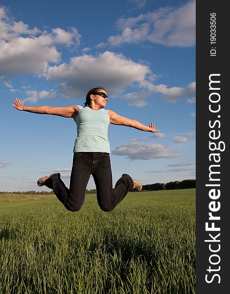 Young woman jumps at green grass field