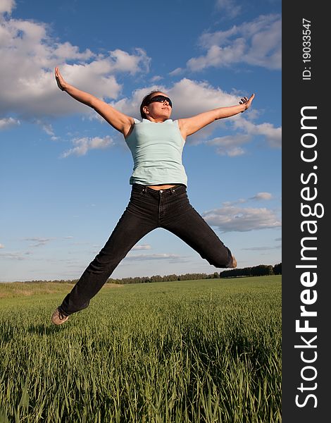 Young woman jumps at green grass field