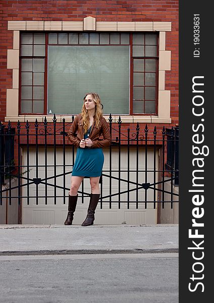 A girl stands in front of an iron gate. A girl stands in front of an iron gate.