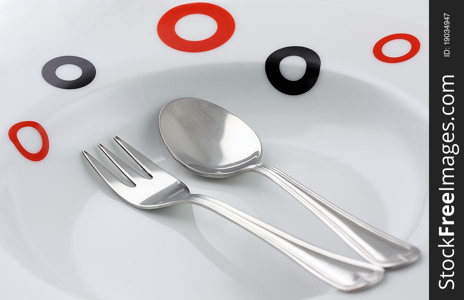 Plate, spoon and fork on dark background. Plate, spoon and fork on dark background