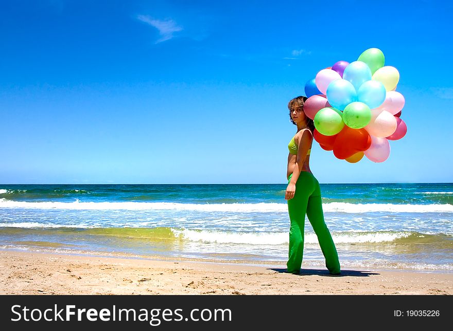Young woman with colorful balloons on the beach