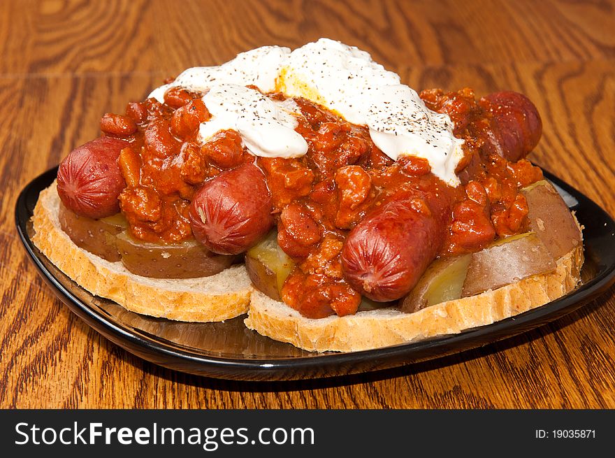 Three Chili dogs on top of potatoes and bread, covered in Sour Cream, Hot Sauce and Pepper. Three Chili dogs on top of potatoes and bread, covered in Sour Cream, Hot Sauce and Pepper