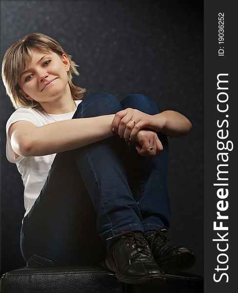 Pretty young girl sitting on a black cube