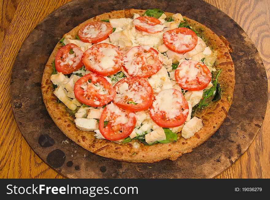 A Pizza made with Tomatoes, Spinach, Steamed Chicken, Pesto, Mozzarella Cheese, and Hand Made Crust. A Pizza made with Tomatoes, Spinach, Steamed Chicken, Pesto, Mozzarella Cheese, and Hand Made Crust