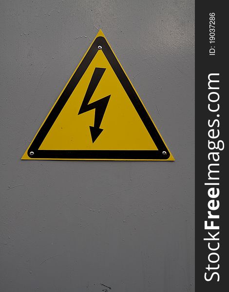 Yellow electricity warning sign on gray background. Yellow electricity warning sign on gray background