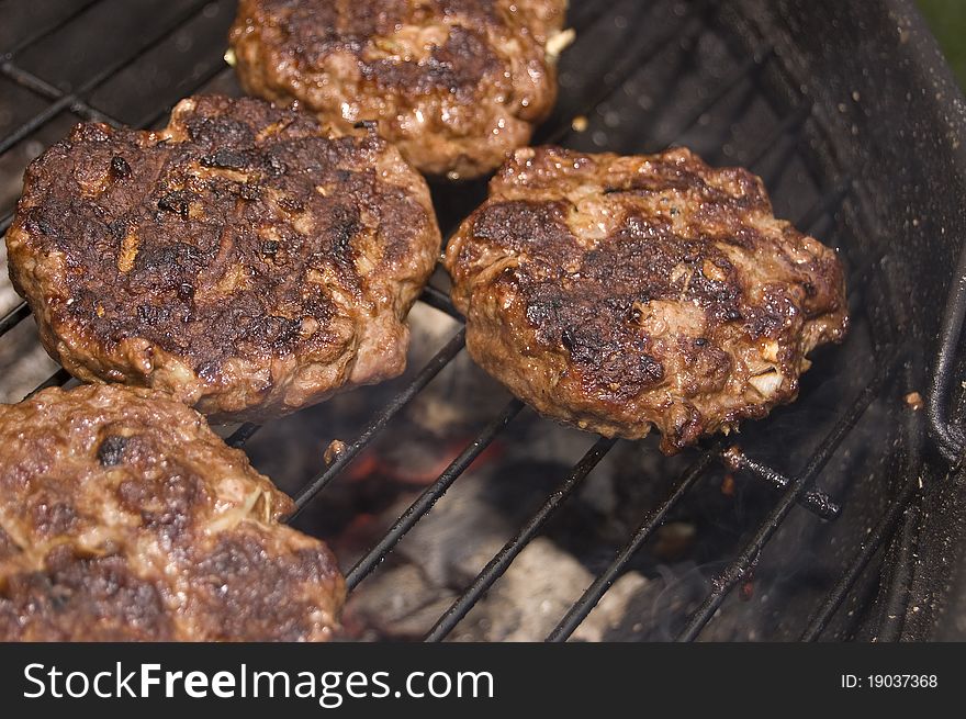 Burgers cooking on barbecue grill over charcoal