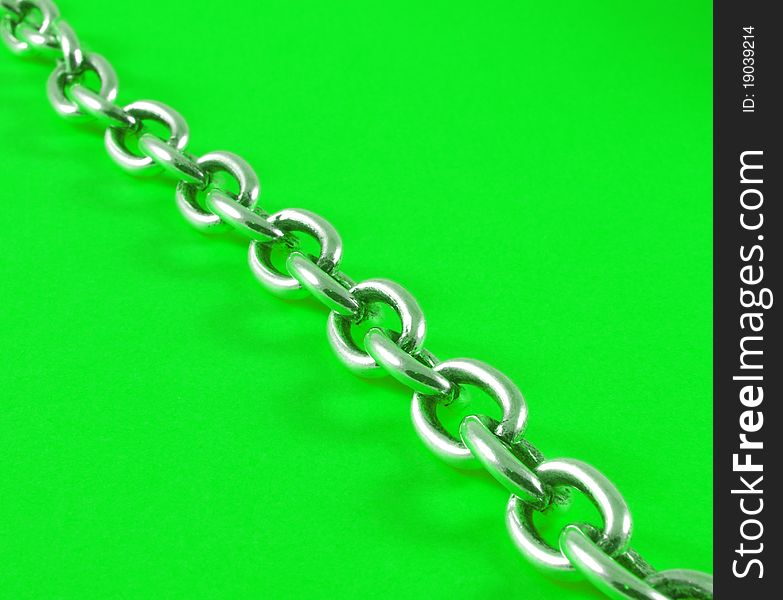 Closeup of steel chain over green background