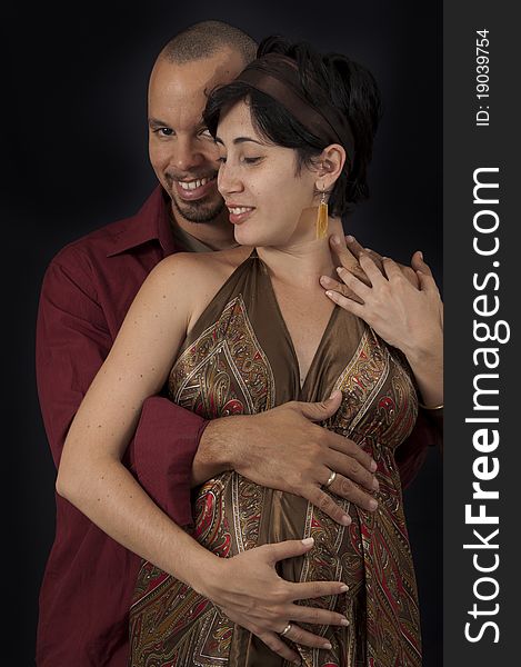 Portrait of young cheerful hispanic couple specting a child, isolated on black. Portrait of young cheerful hispanic couple specting a child, isolated on black