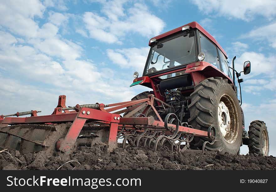 Red tractor plowing the fields