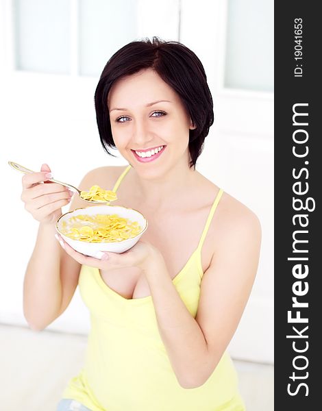 Girl eating cornflakes on a light background