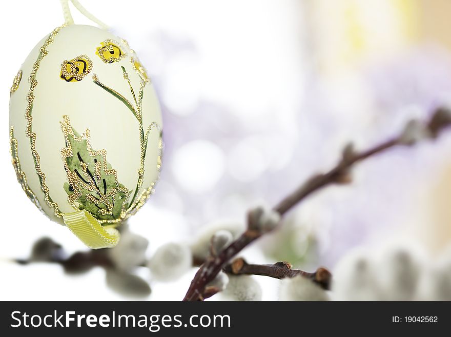 Painted yellow easter egg hanging on catkin branch with purple flowers in background. Painted yellow easter egg hanging on catkin branch with purple flowers in background.