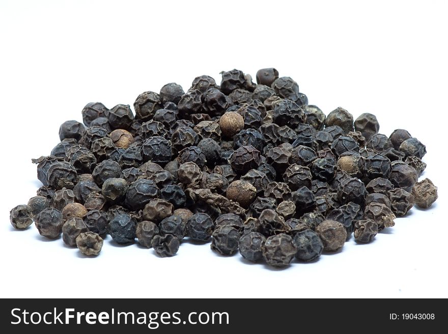 Dried black peppers in white background