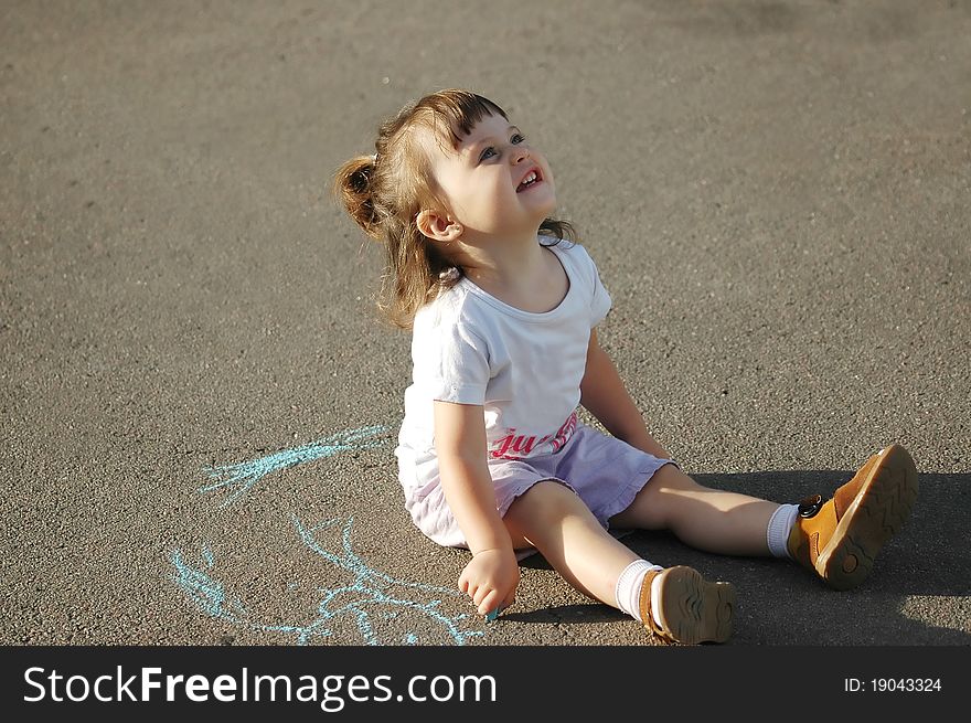 The child drawing a chalk on asphalt-outdoors