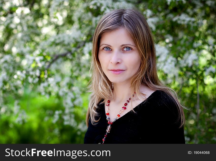 Beautiful woman portrait outdoor with blooming trees in spring as background. Beautiful woman portrait outdoor with blooming trees in spring as background