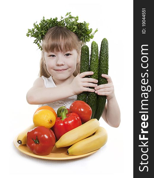 Child holds vegetables and fruit.