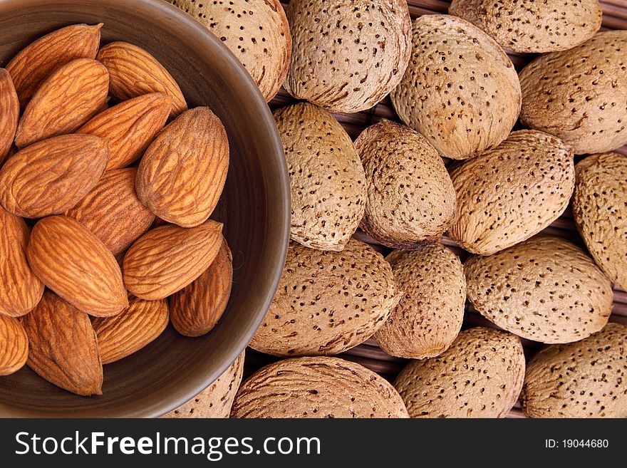 Almond kernels in clay bowl with background of shelled almonds. Almond kernels in clay bowl with background of shelled almonds