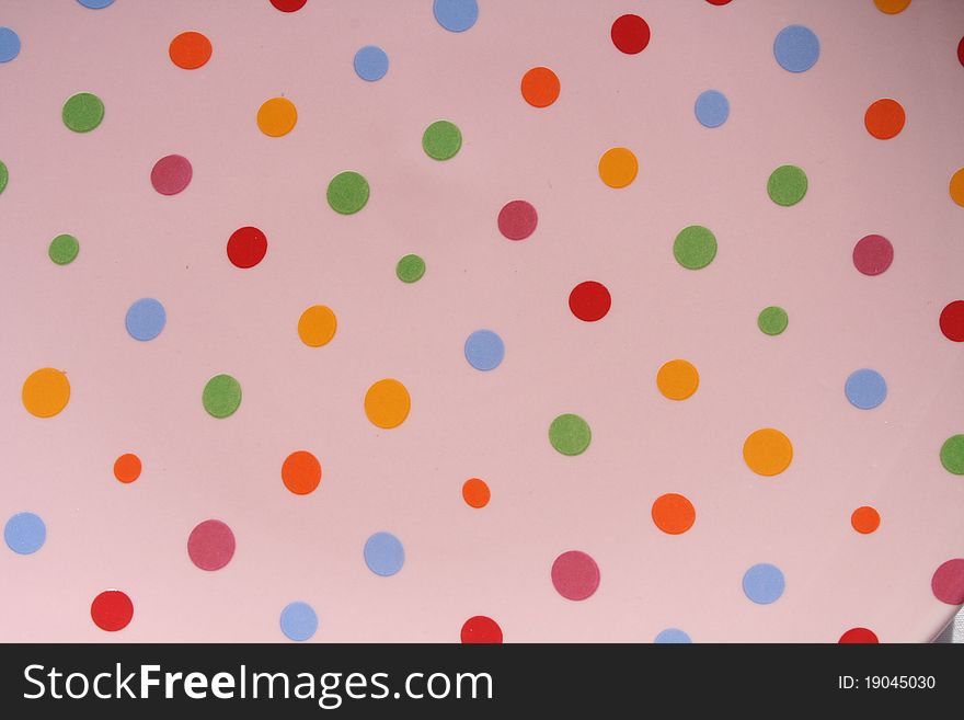 Close up of a pink plate with colorful dots painted on it. Close up of a pink plate with colorful dots painted on it.