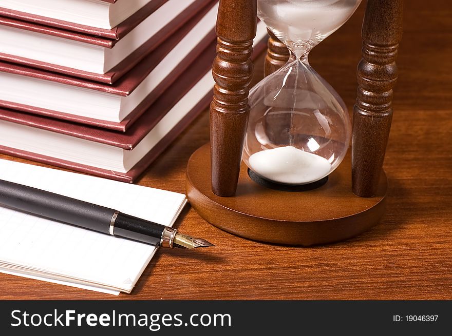 Hourglasses and book on a wooden table