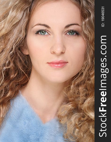 Portrait of the beauty young blond girl with curly hair in blue