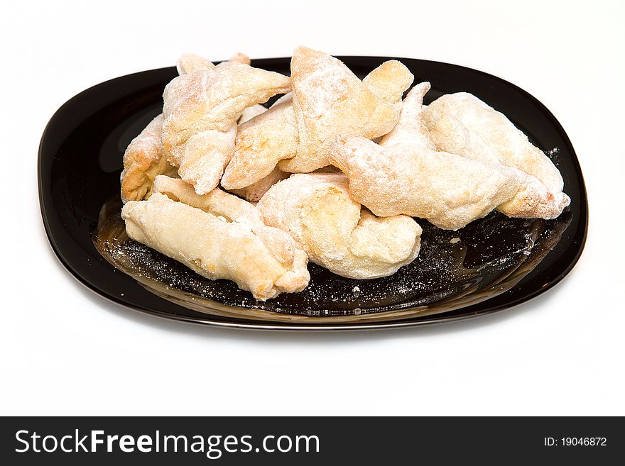Puffed pastry covered with icing sugar on black plate isolated on white background