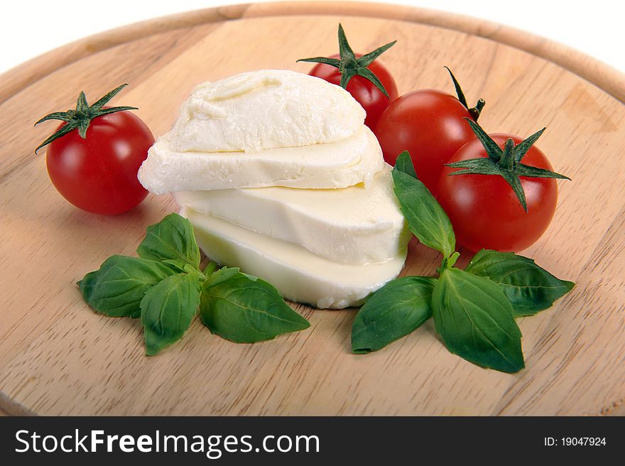 Mozzarella cherry tomatoes basil on a wooden board. Mozzarella cherry tomatoes basil on a wooden board