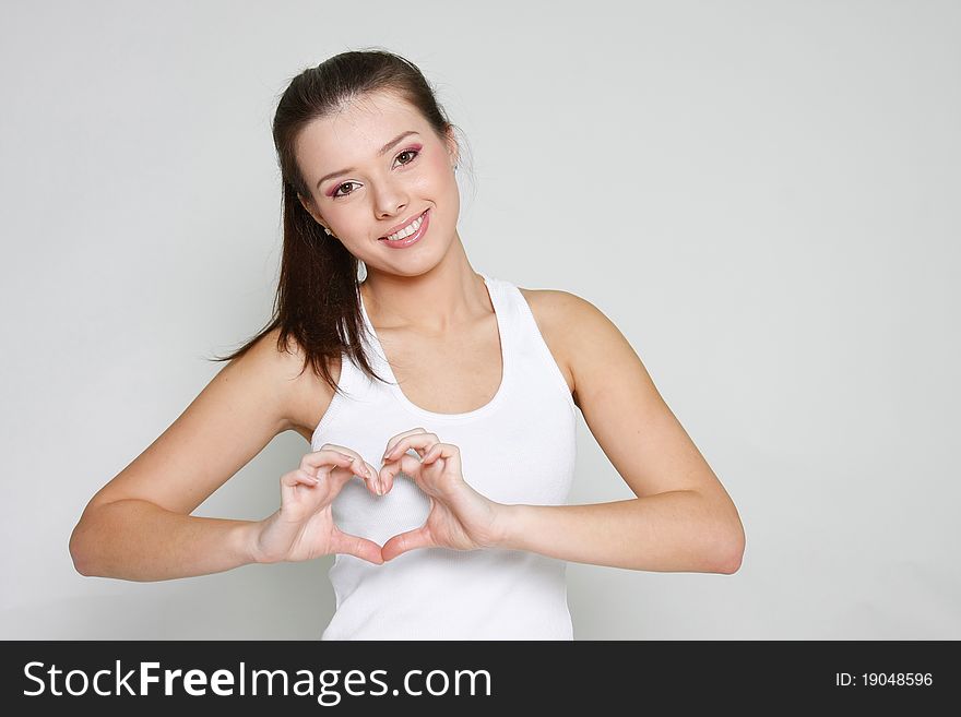 Studio portrait of young attractive girl showing heart shape with her fingers. Studio portrait of young attractive girl showing heart shape with her fingers