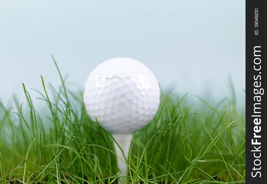 A golf ball on green grass siolated against a blue sky. A golf ball on green grass siolated against a blue sky