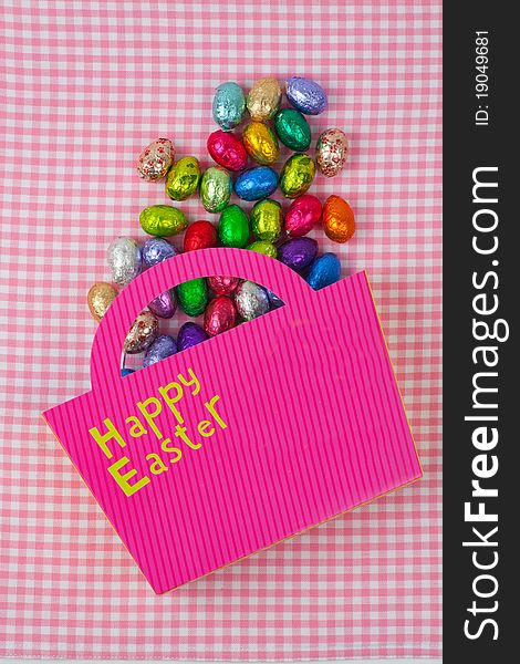 Chocolate Easter eggs falling from a pink bag isolated on a pink background