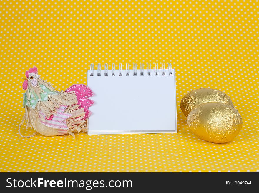 Blank notebook with Easter chocolate eggs isolated on a yellow background. Blank notebook with Easter chocolate eggs isolated on a yellow background