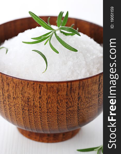 Sea salt with fresh rosemary in wooden bowl closeup