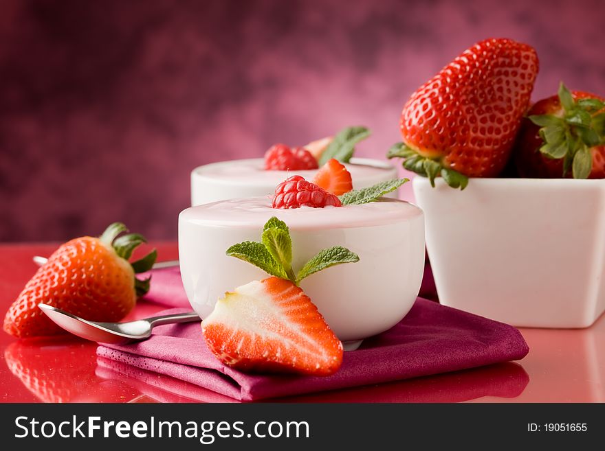 Photo of delicious strawberry yogurt on red glass table. Photo of delicious strawberry yogurt on red glass table