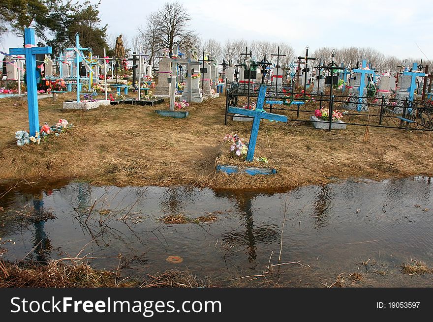 Flooded rural cemetery graves and display the cross in the water. Flooded rural cemetery graves and display the cross in the water