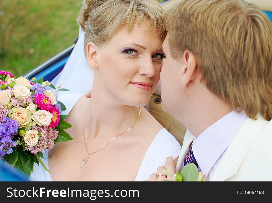 Bride and groom kissing in the car