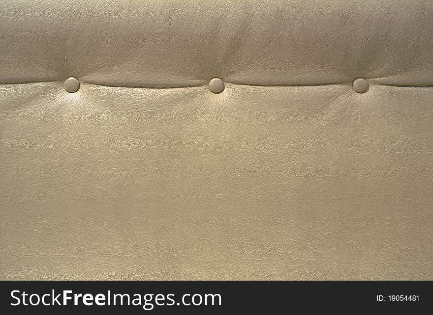 Part of a beige leather seat with three buttons on it.