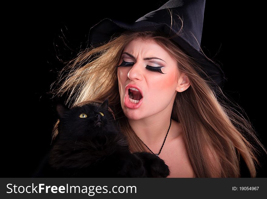 Beautiful girl dressed as a witch holding cat