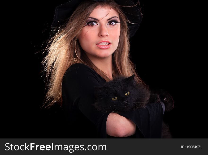 Beautiful girl dressed as a witch holding cat