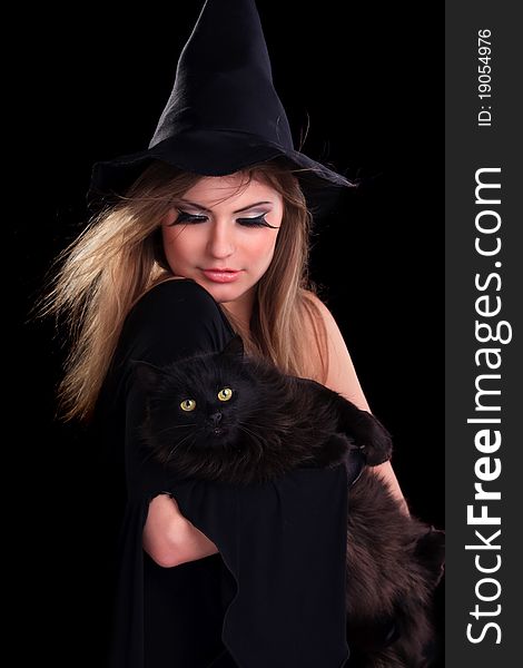 Beautiful girl dressed as a witch holding cat