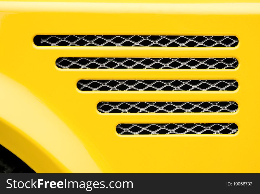 Auto engine grille closeup on a bright yellow vehicle