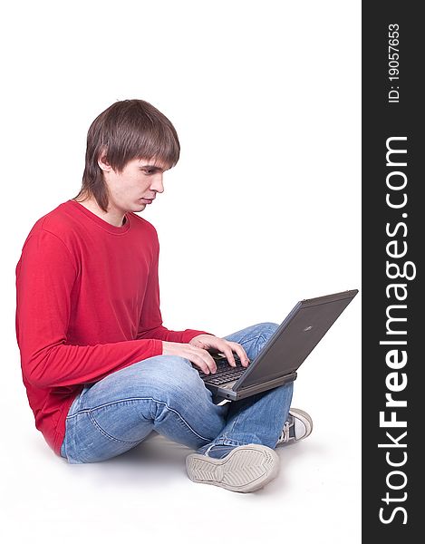 The young man sits on a floor with the laptop. The young man sits on a floor with the laptop